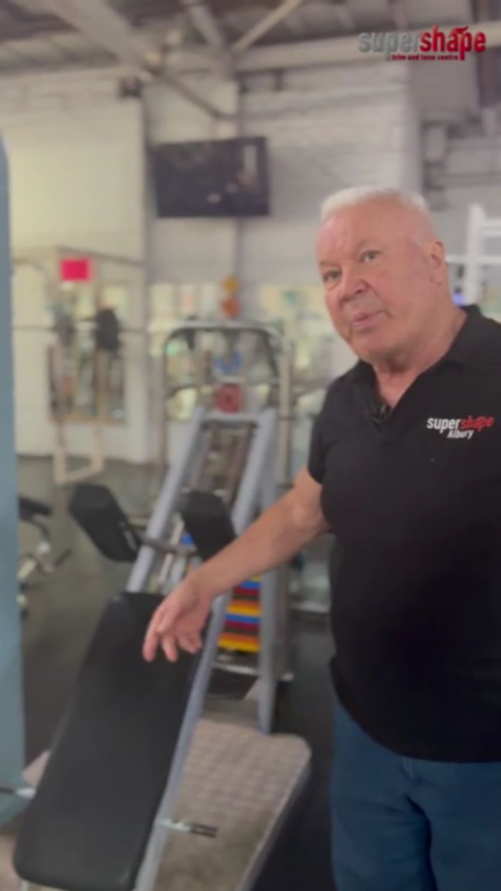 Laurie demonstrating the side-loaded hack squat machine at Supershape Gym.